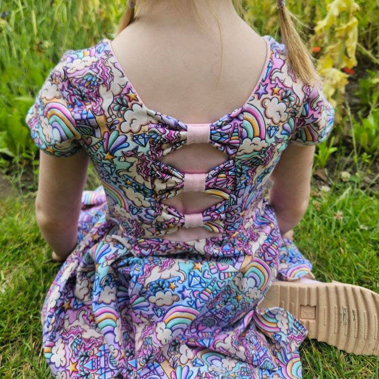 Child wearing a colorful dress with a bow in a garden