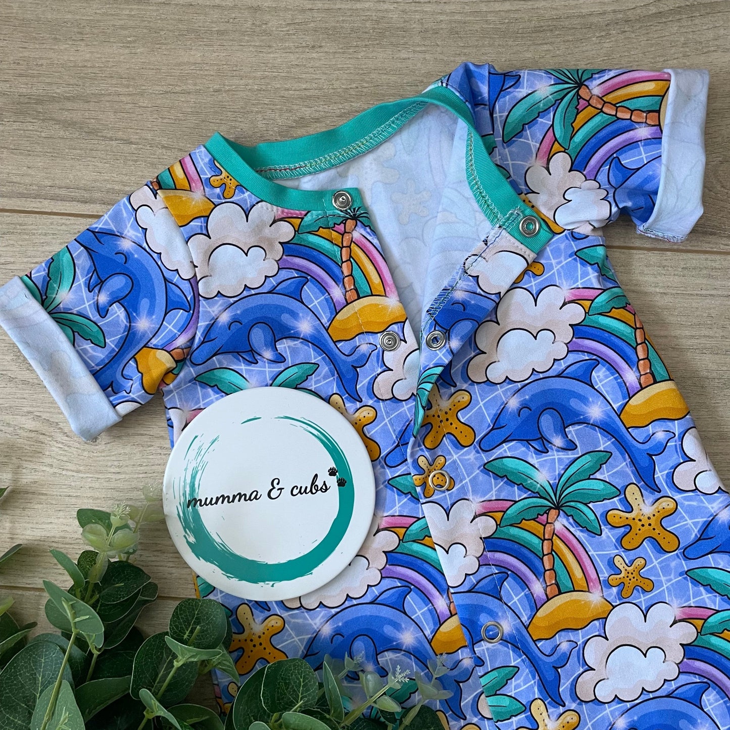 Colorful baby onesie with dolphin, palm tree and raimbow pattern