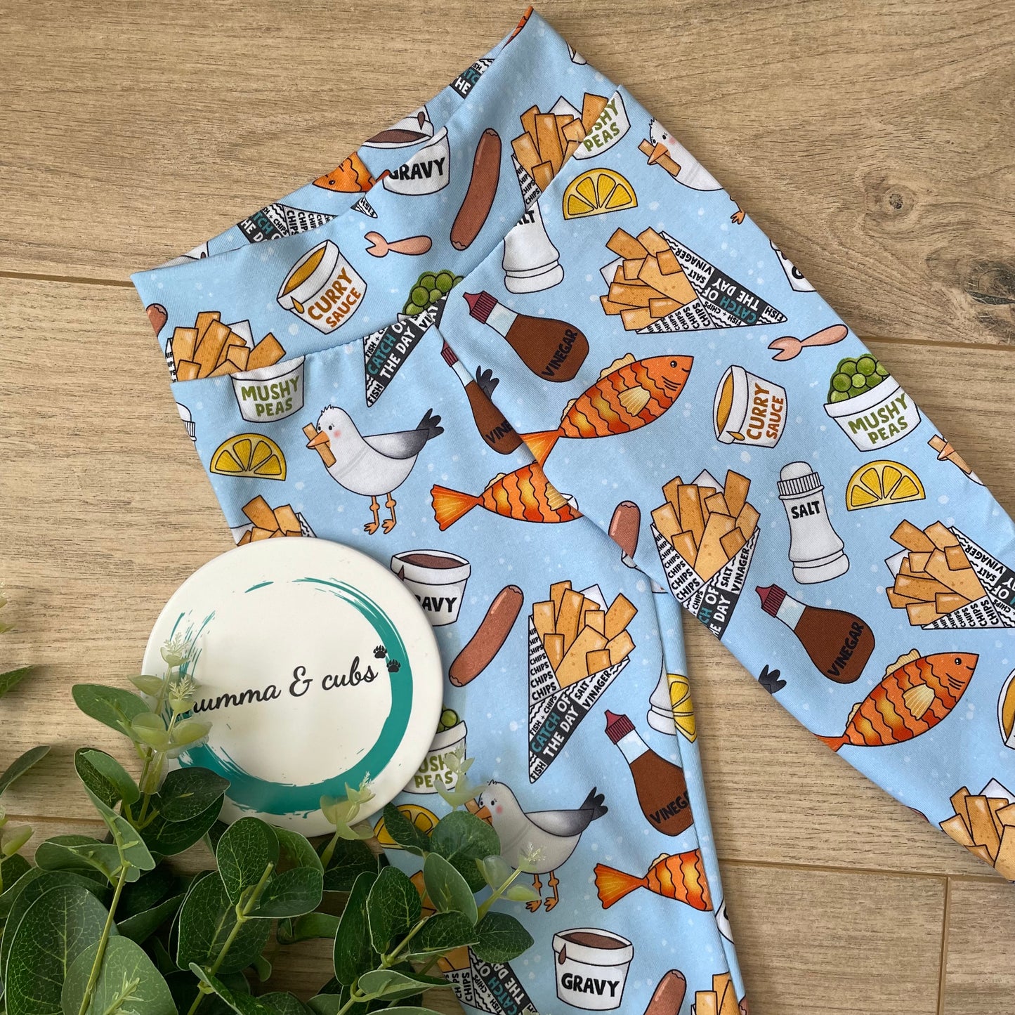 Handmade childrens leggings with a chip shop design. Featuring fish, chips, mushy pease, salt, pepper and more on a light blue background.