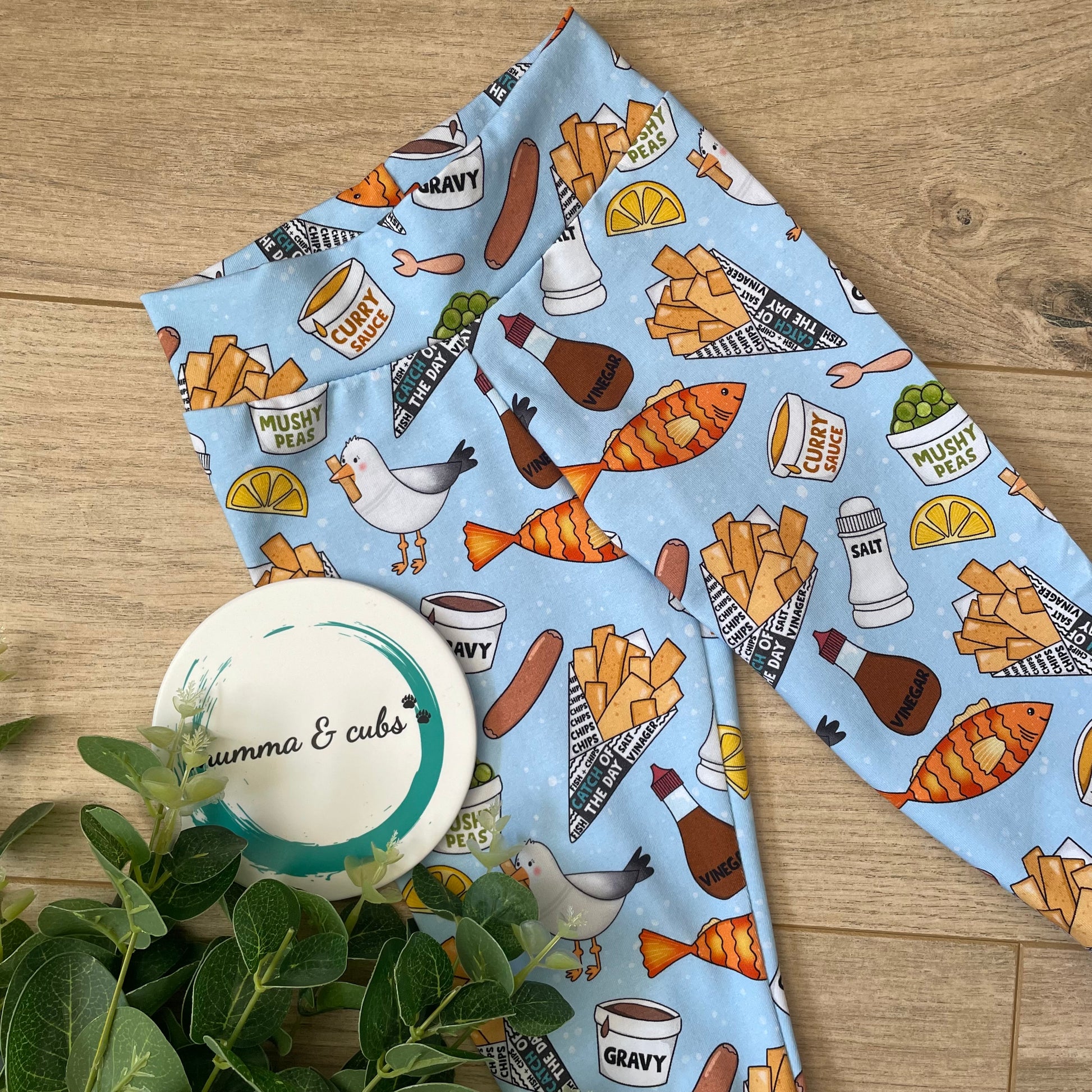 Handmade childrens leggings with a chip shop design. Featuring fish, chips, mushy pease, salt, pepper and more on a light blue background.