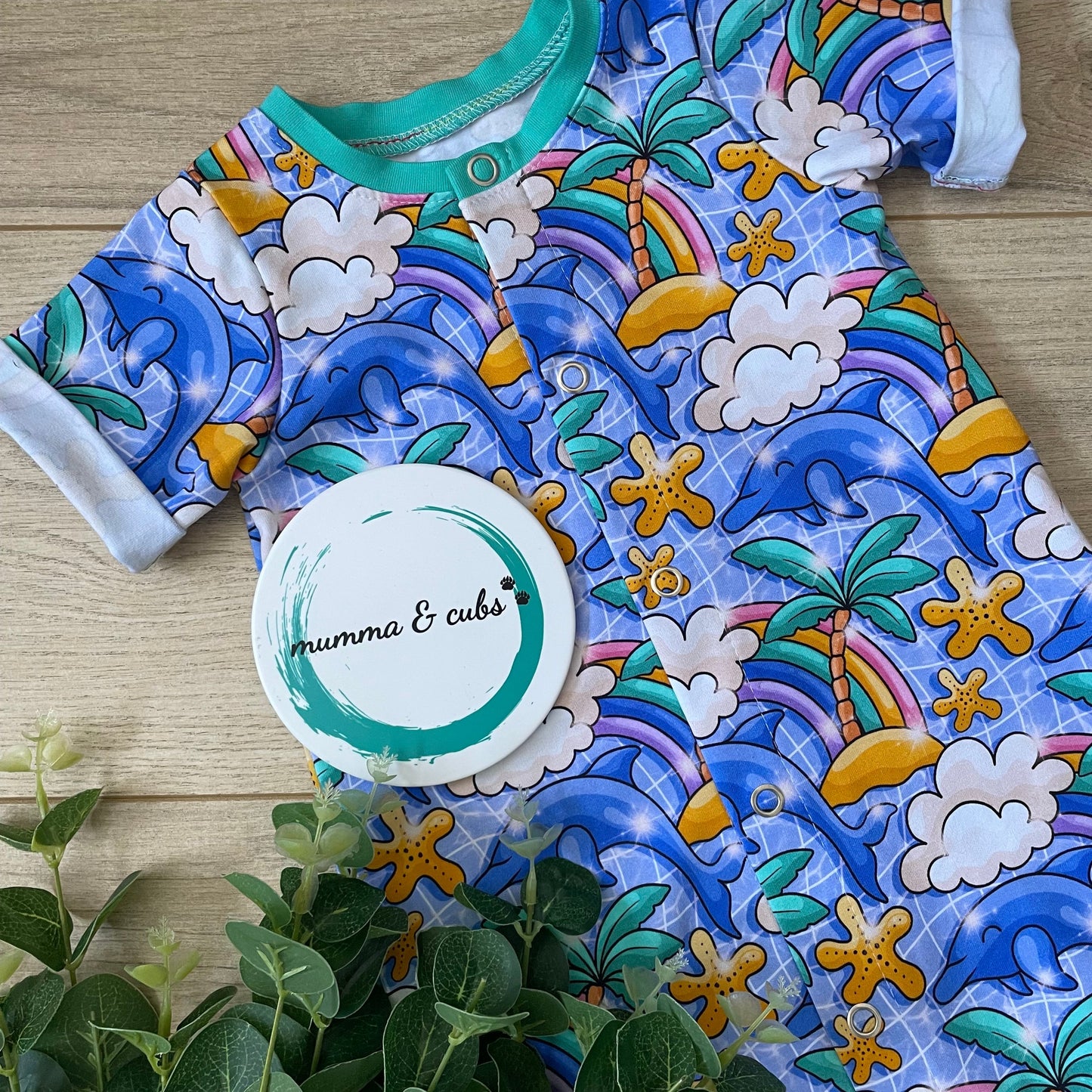 Colorful baby outfit with sea-themed pattern on a wooden surface