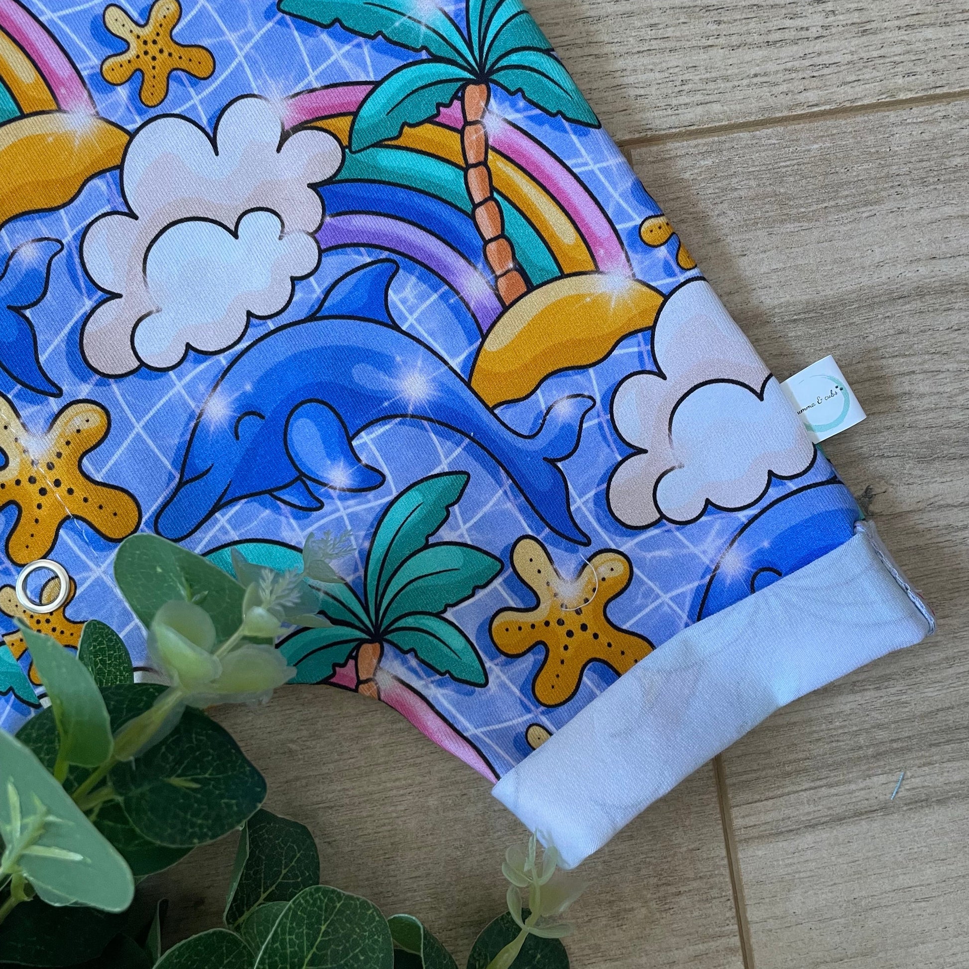 Colorful fabric with dolphins, stars, and clouds on a wooden surface.