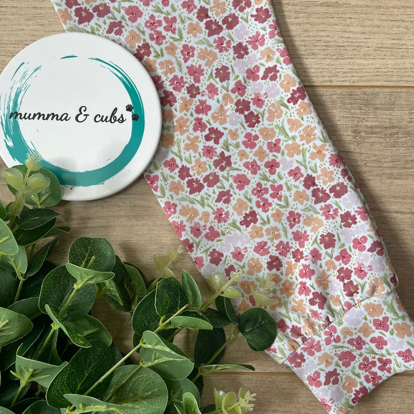 Floral-patterned product with a 'mumma & Cubs' branded item on a wooden surface.