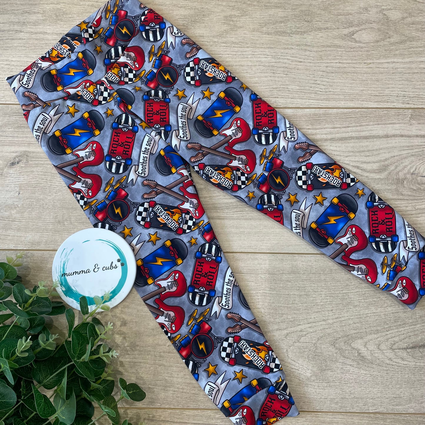 Chldrens leggings made from fabric with rock guitars and skateboards with drum kids on a grey background.