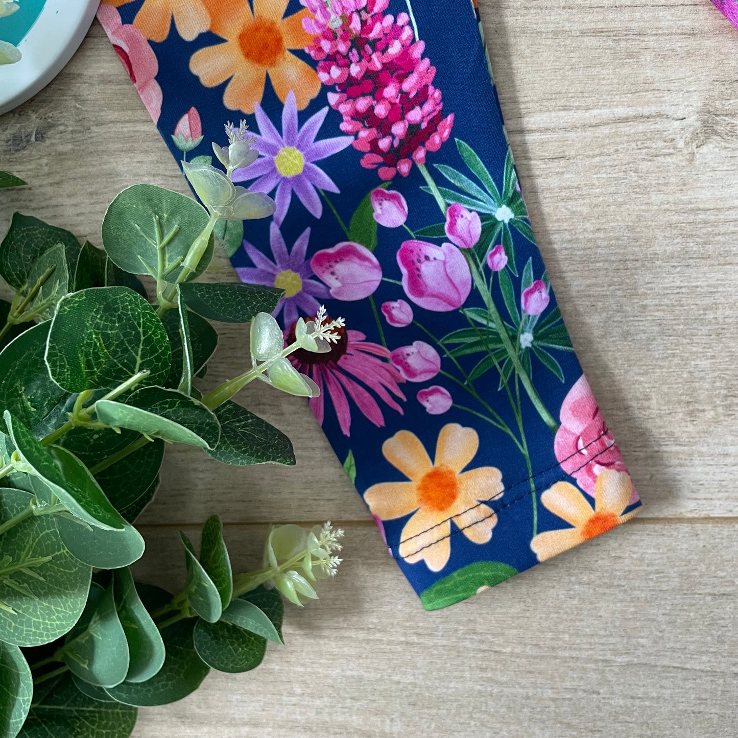 Floral-patterned fabric with colorful flowers showing hemmed leg detail on kids leggings