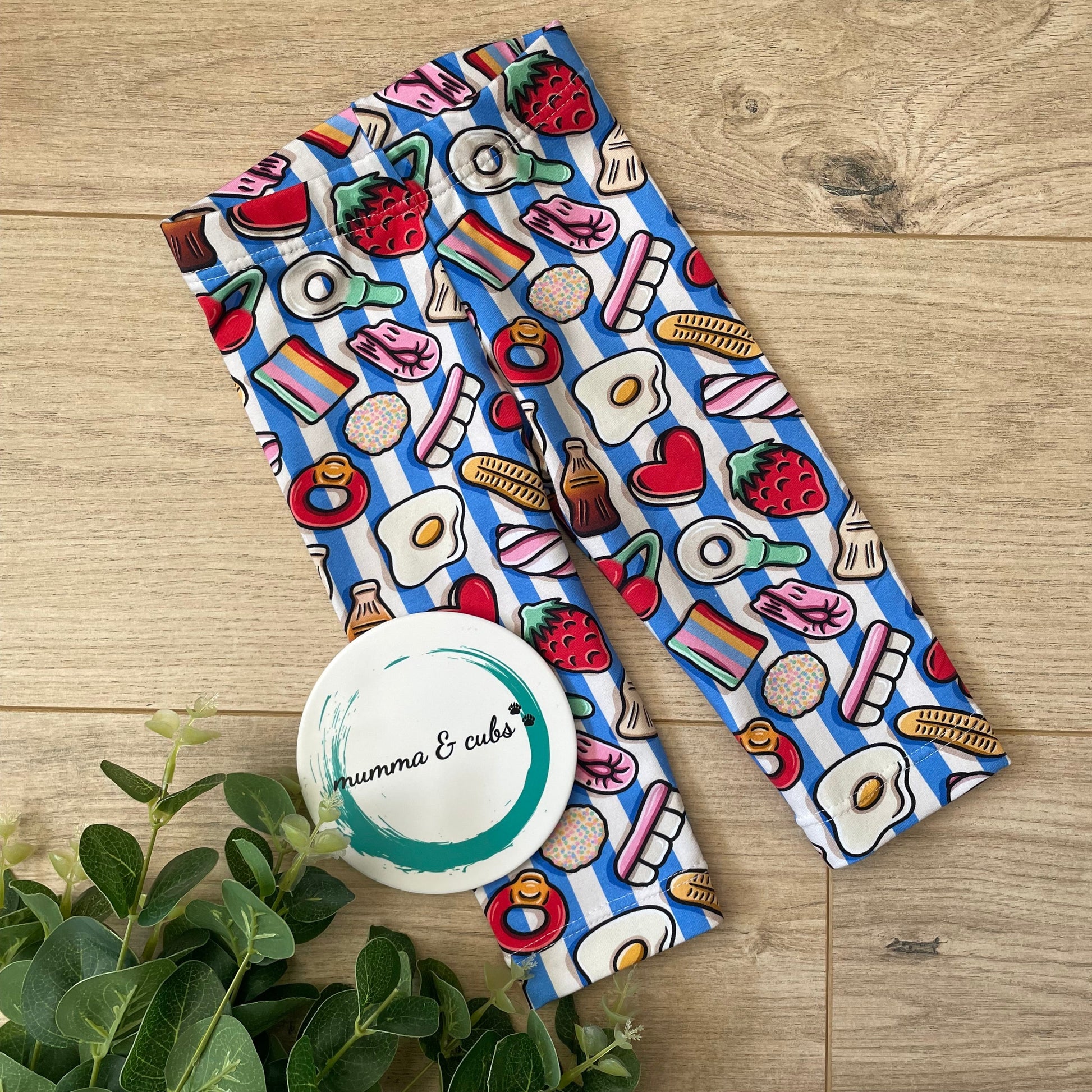 Childrens leggings with a sweetshop favourites including strawberries, eggs, cola botles design on a blue and white striped background